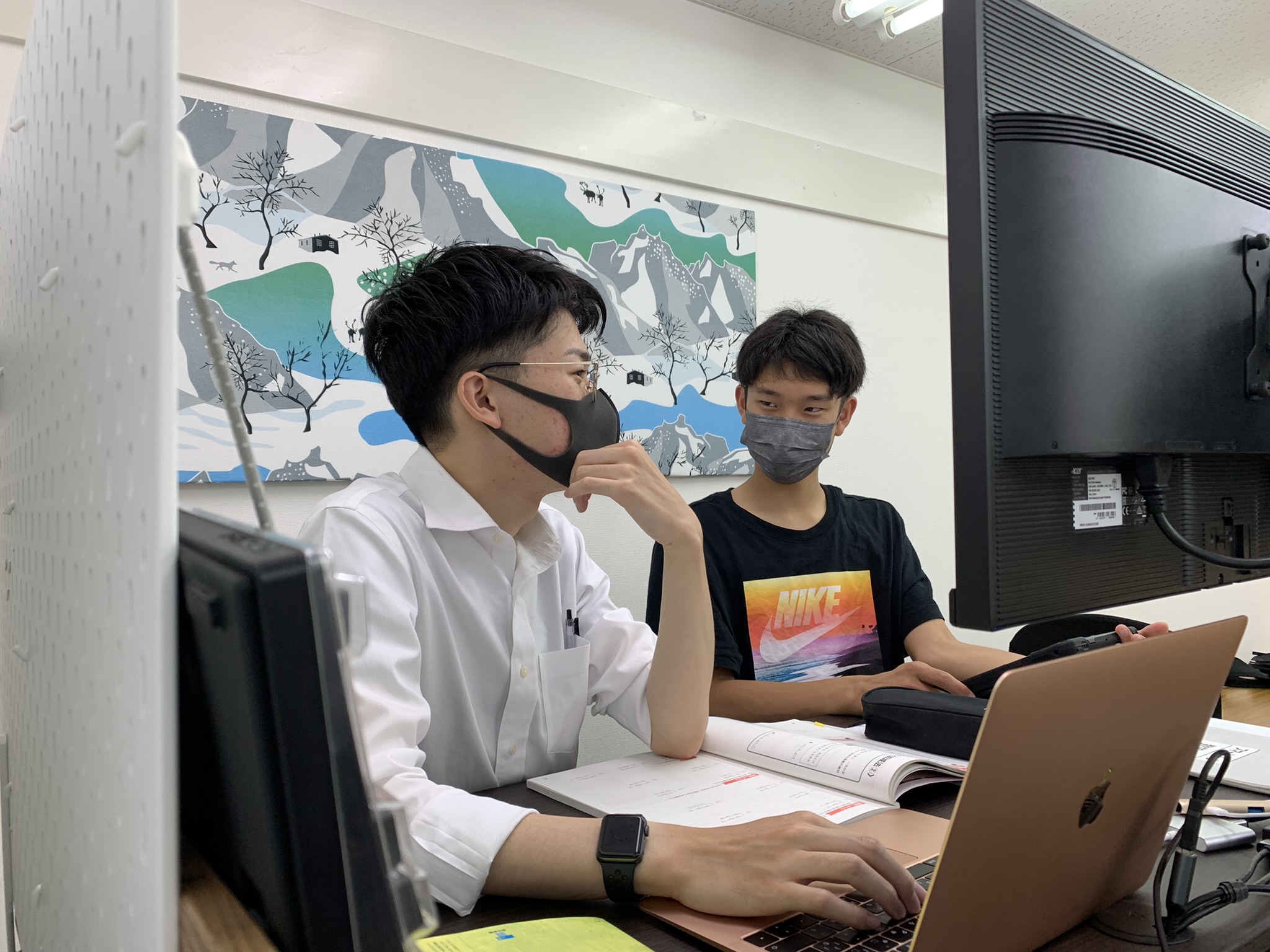 生徒と対話しながらパソコンと教材で指導する講師